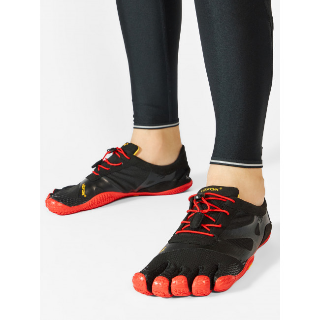 Sapatos Fivefingers Vibram pretos masculinos com cadarços vermelhos e solas vermelhas nas pernas em leggings