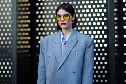 Milão, Itália 25 de fevereiro um convidado usa óculos de sol amarelos, brincos de prata, uma jaqueta de blazer oversized cinza pálido com epaulets, uma camisa oversized azul claro azul bebê branco, fora do desfile da gucci, durante a semana de moda de Milão Outono 20222023 em 25 de fevereiro de 2022 em Milão, Itália Foto tirada por Edward Berthelotgetty Images